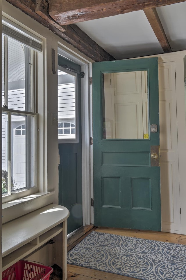 doorway with wood finished floors, a healthy amount of sunlight, and beam ceiling