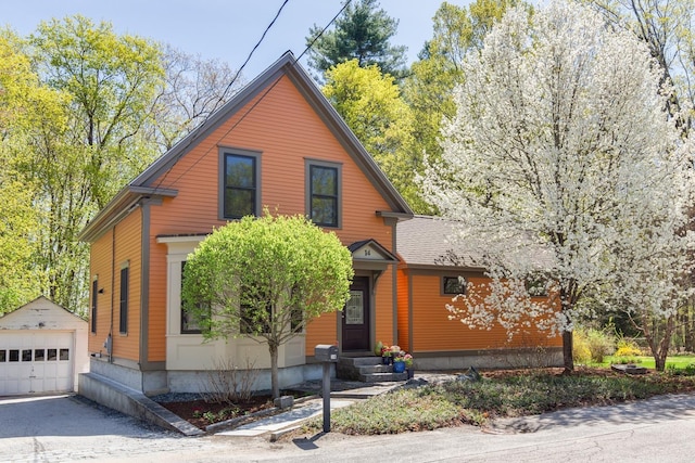 view of front of property featuring entry steps, a detached garage, an outbuilding, and aphalt driveway