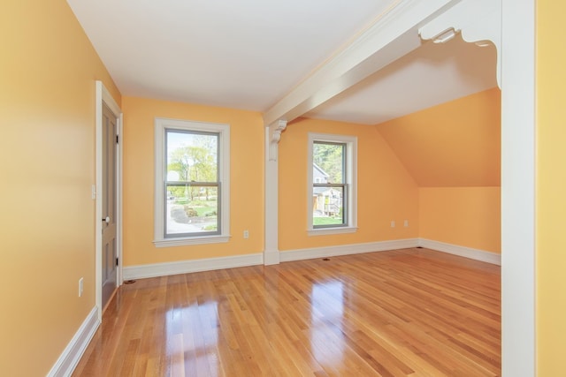 bonus room with light wood-style floors, baseboards, and vaulted ceiling