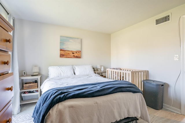 bedroom with baseboards, visible vents, and wood finished floors
