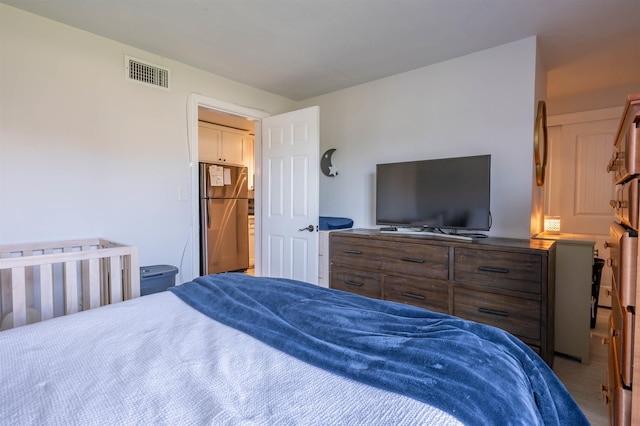 bedroom featuring freestanding refrigerator and visible vents