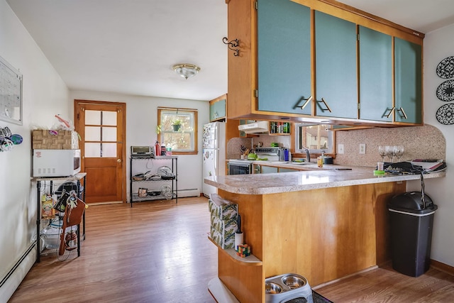 kitchen with light wood-style floors, white appliances, light countertops, a peninsula, and blue cabinets