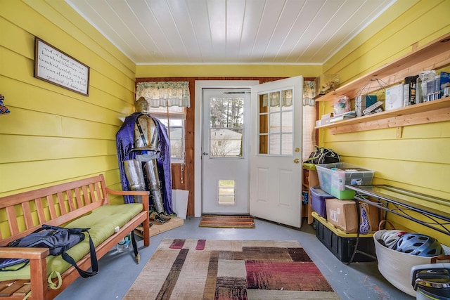 mudroom featuring wooden walls, ornamental molding, and concrete flooring