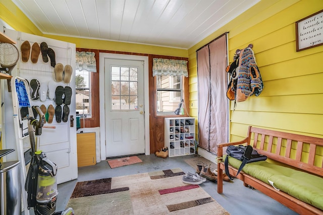 interior space with wooden walls, ornamental molding, and concrete flooring