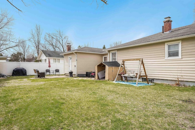 back of property featuring a lawn, fence, and a chimney
