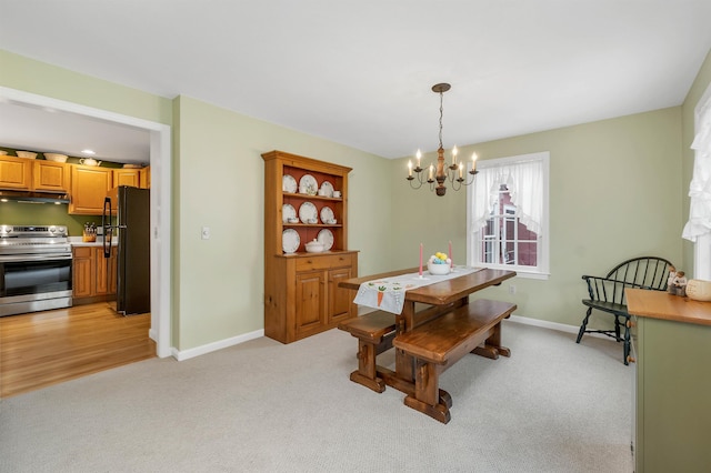 dining space with light colored carpet, baseboards, and a chandelier