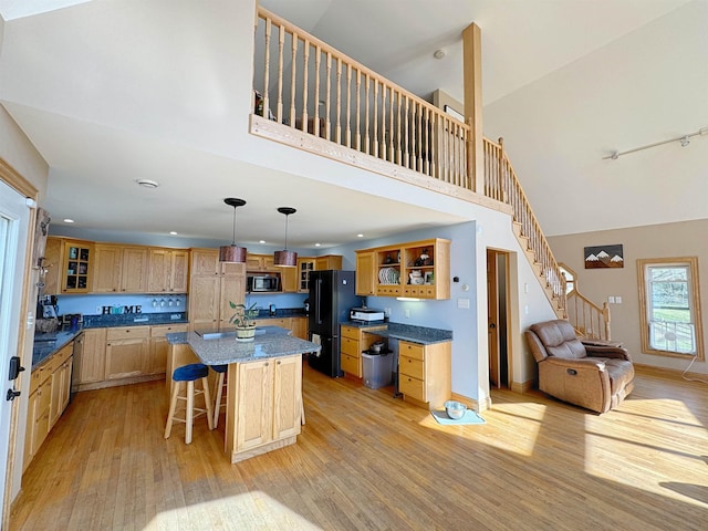 kitchen with freestanding refrigerator, open shelves, high vaulted ceiling, a kitchen bar, and light wood-style flooring