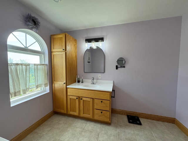 bathroom featuring baseboards, tile patterned flooring, vanity, and lofted ceiling