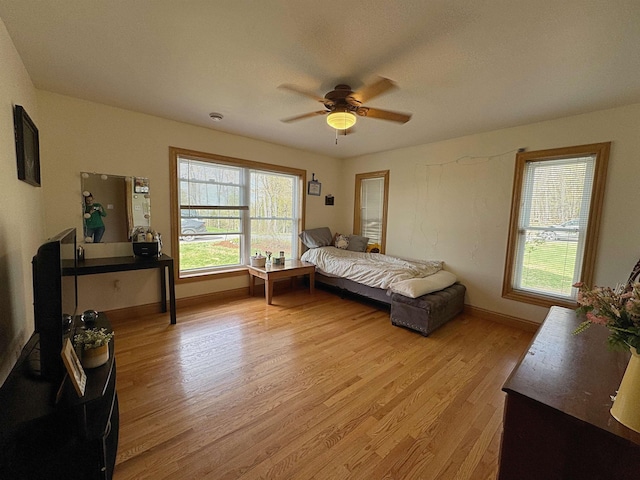bedroom featuring baseboards, light wood finished floors, and ceiling fan