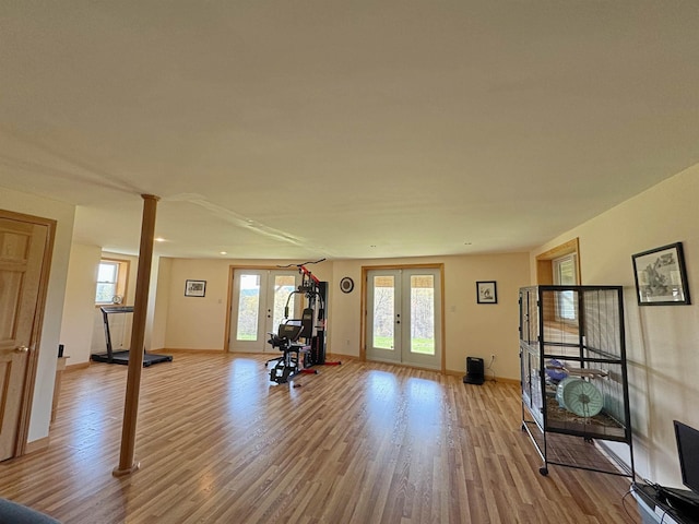 exercise area with ornate columns, baseboards, french doors, and light wood-style floors