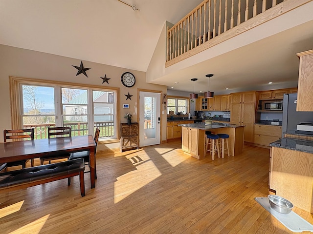 dining room with recessed lighting, light wood finished floors, and high vaulted ceiling
