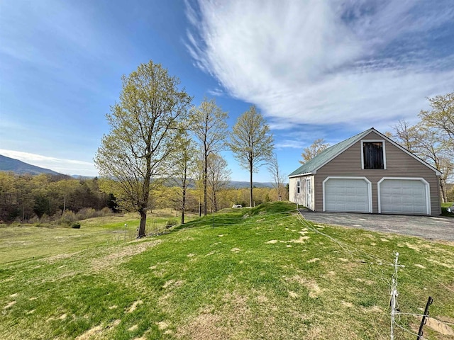 view of yard with a garage, an outbuilding, and aphalt driveway