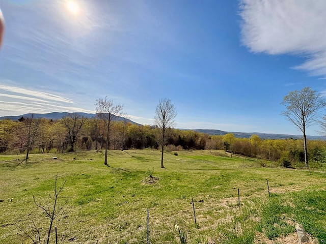 exterior space featuring fence, a mountain view, and a rural view