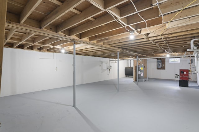 below grade area with heating fuel, electric panel, and electric water heater