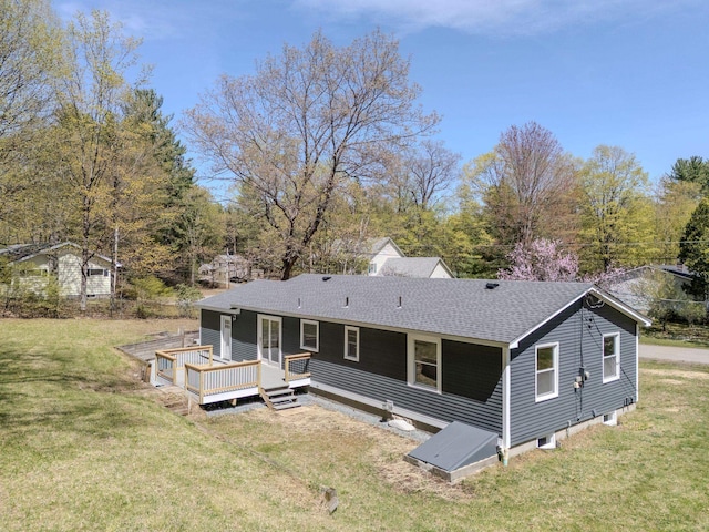 back of property featuring a yard, a deck, and a shingled roof