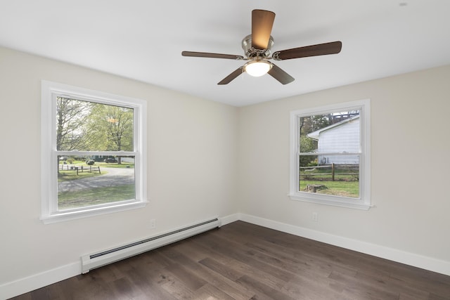 spare room with baseboards, a baseboard heating unit, dark wood finished floors, and a wealth of natural light