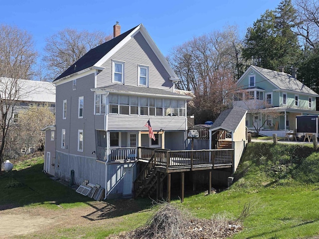 back of property with stairway, a deck, a chimney, and a lawn