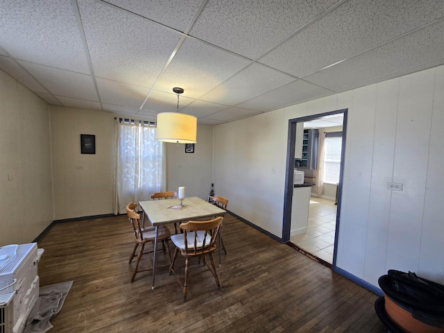 dining room with wood-type flooring, baseboards, and a paneled ceiling