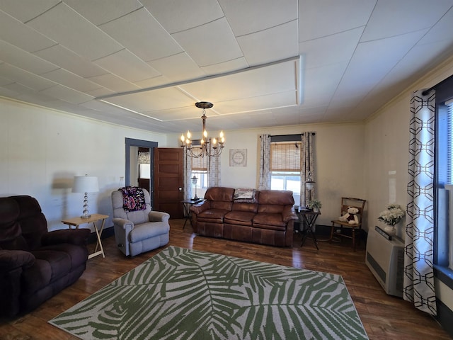 living area featuring crown molding, a chandelier, and dark wood-type flooring