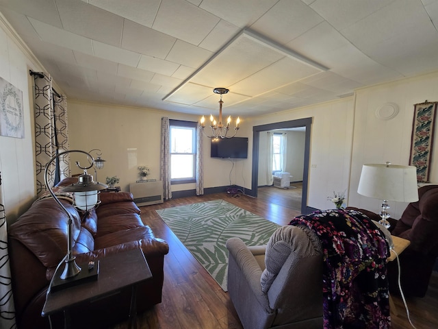living area with crown molding, baseboards, an inviting chandelier, and wood finished floors