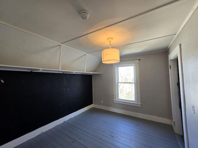 unfurnished dining area featuring wood-type flooring, baseboards, and vaulted ceiling
