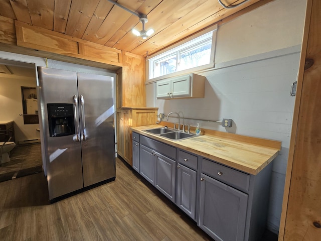 kitchen with stainless steel fridge, a sink, wooden counters, gray cabinets, and dark wood-type flooring