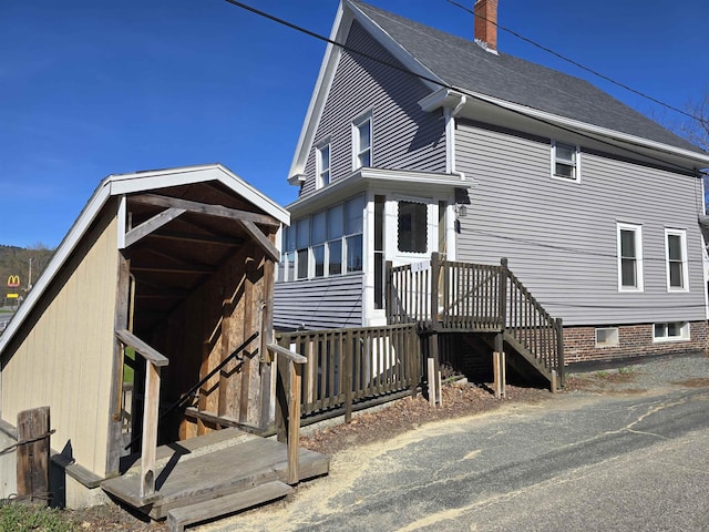 back of property with a chimney and roof with shingles