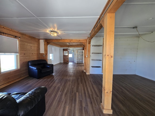 unfurnished living room with baseboards, wood walls, and dark wood-style floors