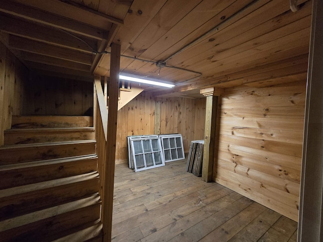 finished basement with wooden walls, stairway, and wood-type flooring