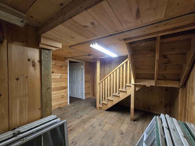 finished basement featuring stairs, wood walls, wood ceiling, and light wood-type flooring