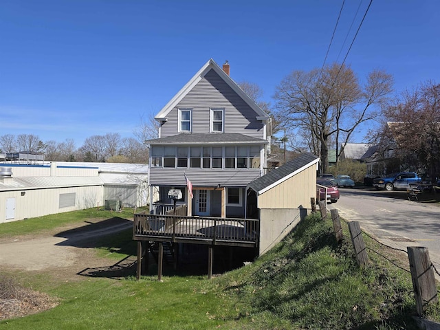 rear view of property with roof with shingles, a chimney, and a deck