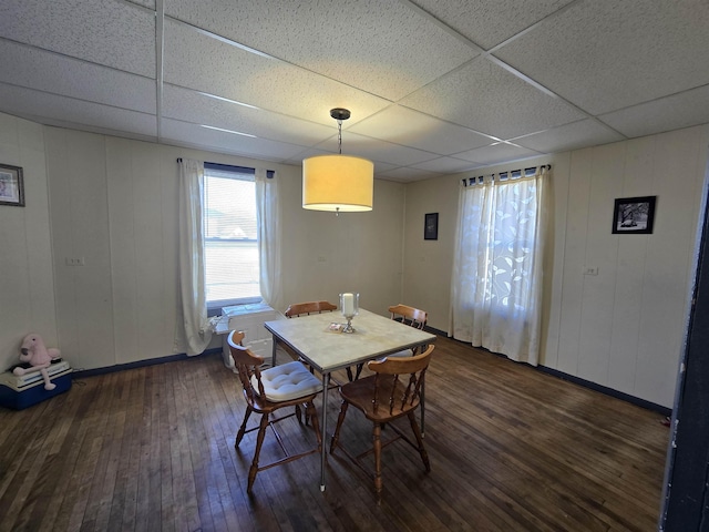 dining space with wood-type flooring, baseboards, and a paneled ceiling