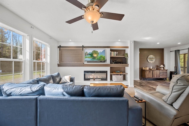 living room with recessed lighting, a ceiling fan, and a glass covered fireplace