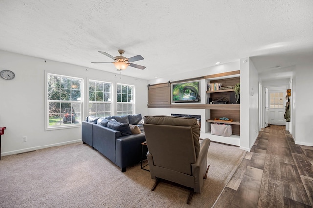 living area featuring baseboards, a ceiling fan, a textured ceiling, and wood finished floors