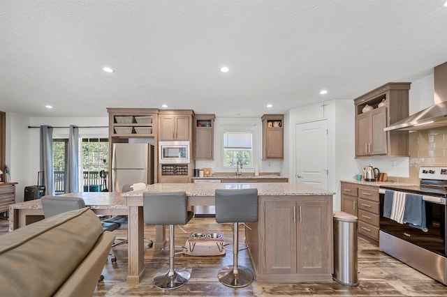 kitchen with open shelves, appliances with stainless steel finishes, wood finished floors, and a kitchen island