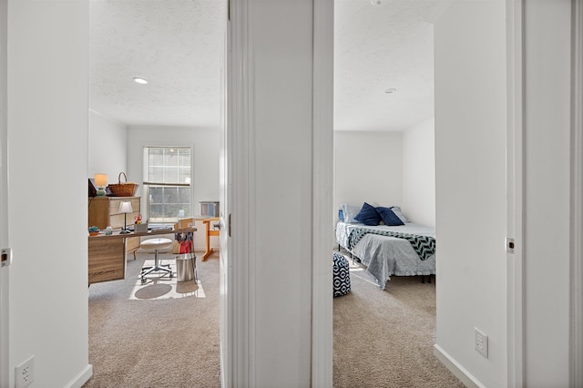 corridor featuring baseboards, carpet flooring, and a textured ceiling