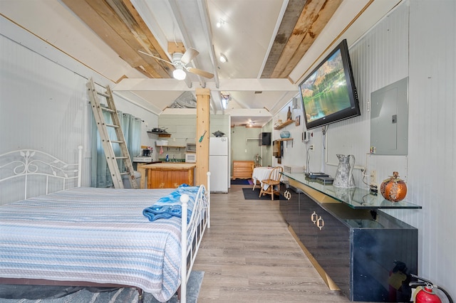 bedroom with light wood-style floors, vaulted ceiling with beams, freestanding refrigerator, and electric panel