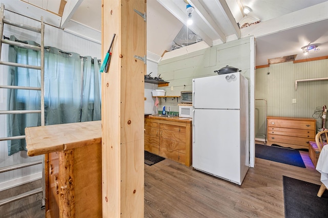 kitchen featuring white appliances, lofted ceiling with beams, and wood finished floors