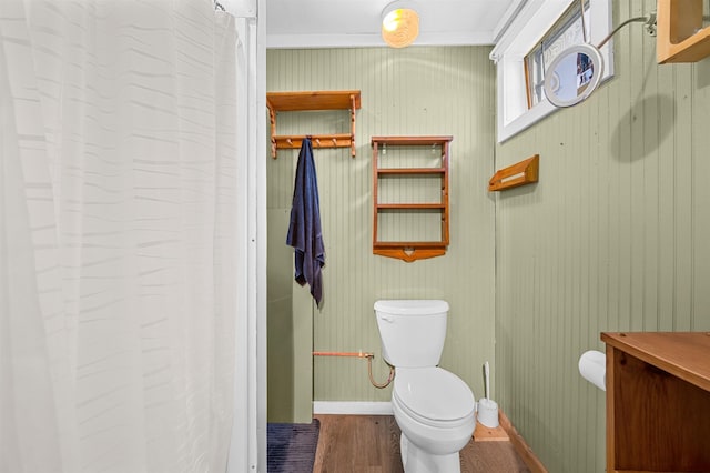 bathroom featuring baseboards, wood finished floors, and toilet