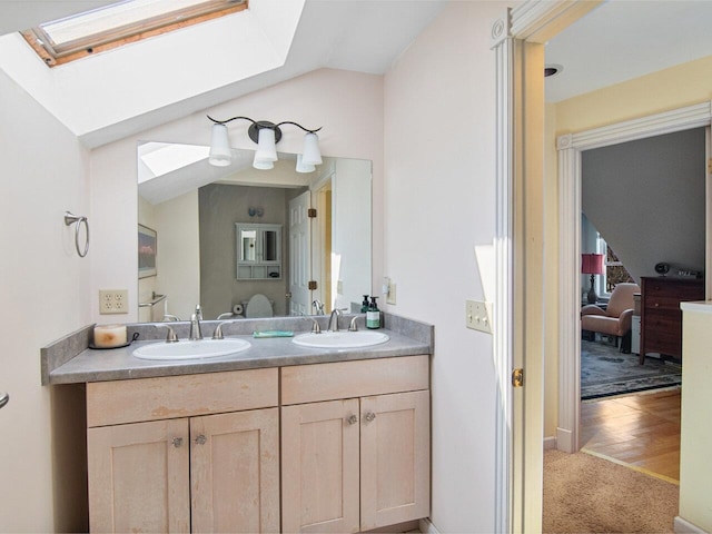 bathroom featuring double vanity, a sink, and vaulted ceiling with skylight