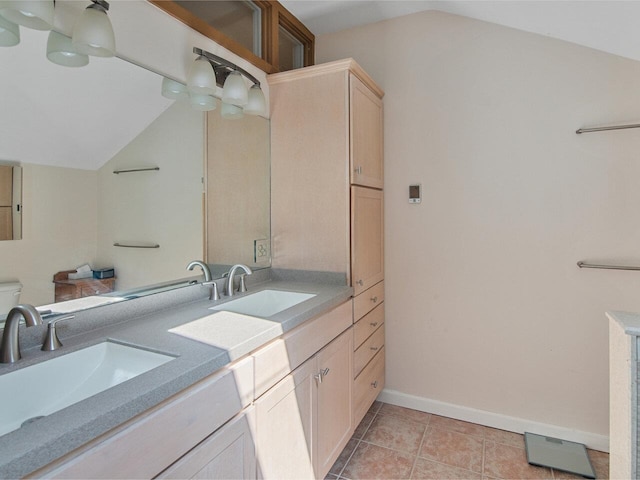 bathroom with a sink, baseboards, double vanity, and lofted ceiling