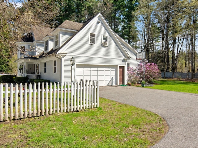 view of property exterior with a yard, a garage, fence, and aphalt driveway