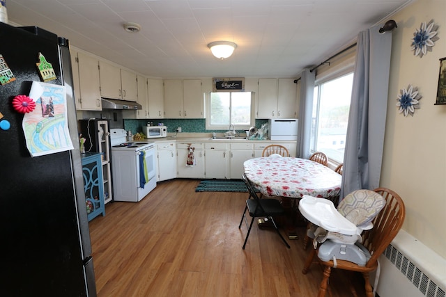 kitchen with plenty of natural light, light wood-type flooring, under cabinet range hood, and white appliances