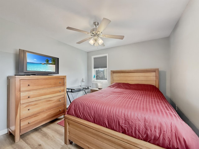 bedroom with baseboards, a ceiling fan, and light wood-style flooring