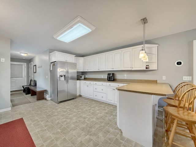 kitchen with white cabinets, open shelves, stainless steel fridge, a breakfast bar area, and a peninsula