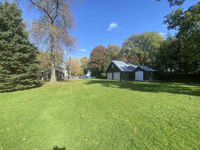view of yard with a garage, an outbuilding, and a shed