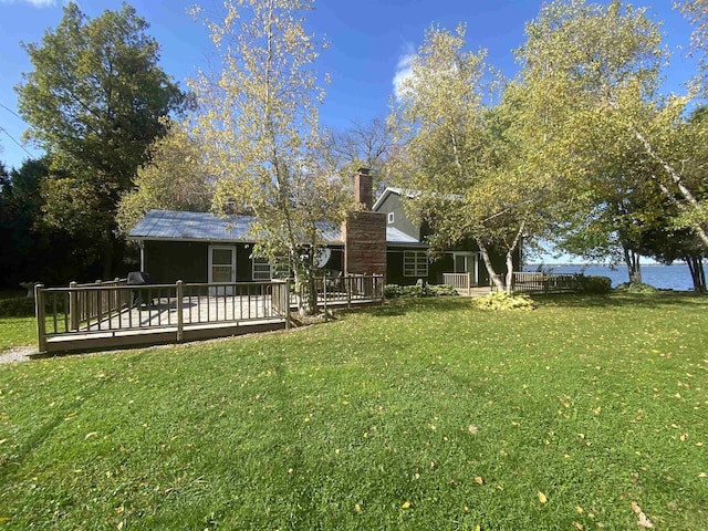 rear view of house featuring a chimney, a yard, and a deck