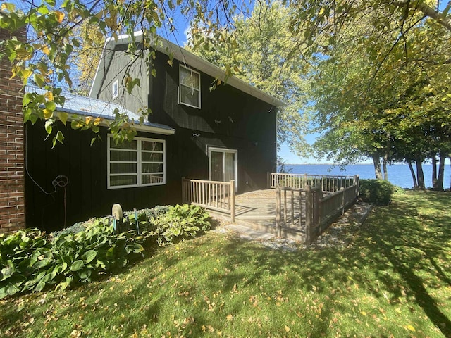 exterior space with a deck with water view and a front lawn