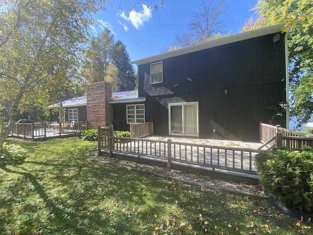 back of property featuring a wooden deck, a chimney, and a yard