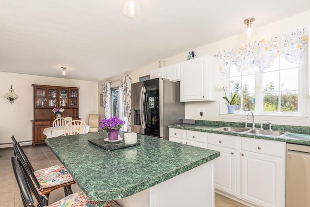 kitchen featuring dark countertops, dishwashing machine, a kitchen breakfast bar, stainless steel refrigerator with ice dispenser, and a sink
